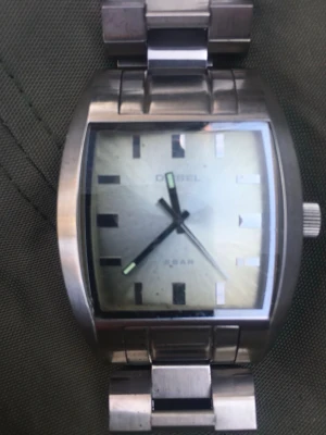 Diesel silverfärgad armbandsklocka - Stilren armbandsklocka från Diesel i silverfärgat rostfritt stål. Klockan har en rektangulär urtavla med minimalistiska markeringar och länkarmband. Passar dig som gillar en modern och robust look.