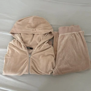 Beige velour loungewear-set med hoodie - Mysigt loungewear-set från Bik Bok i beige velour. Setet består av en hoodie med dragkedja och matchande byxor med breda muddar. Perfekt för chill dagar hemma eller när du vill vara extra bekväm.