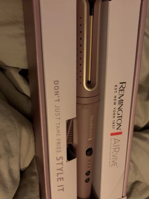 Remington Airwave roterande locktång - Remington Airwave är en roterande locktång i en snygg matt rosa färg med gulddetaljer. Den har ergonomisk form och flera knappar för enkel användning. Perfekt för att skapa lockar och volym. Levereras i originalförpackning. Endast testad! Fint skick! 