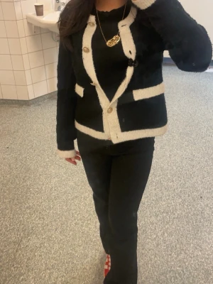 Svart kofta med vita detaljer - Snygg svart kofta med vita kanter och dekorativa knappar. Koftan har långa ärmar och två fickor framtill. Klassisk och stilren design som passar till många outfits. Mjuk och bekväm, perfekt för lager på lager. Pris kan diskuteras!❤️