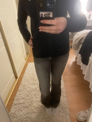 Grå bootcut jeans med vita sömmar - Använda max 10 gånger så har inga tydliga märken att de är använda, väldigt minimalt slitage längst ner på byxorna som syns på bild💞Ett par grå bootcut jeans med tydliga vita kontrastsömmar och låg midja. Jeansen har dubbla knappar framtill och fickor med dekorativa detaljer. Perfekta för dig som gillar en retro och avslappnad stil.