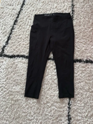 Svarta leggings från Basic You - Svarta leggings från Basic You i mjuk och stretchig ekologisk bomull. De har en hög midja och sitter tight, perfekta till både chill och träning. Enkel och clean design utan detaljer eller mönster. Leggingsen är korta i benen och slutar vid halva vaddmuskeln! Fick dem av mormor och kommer aldrig till användning, tror dock inte heller mormor använt dem!