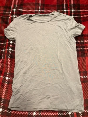 Ljusgrå/beige basic t-shirt från 157 - En enkel och stilren ljusgrå/beige t-shirt från 157. T-shirten har rund halsringning och korta ärmar. Tillverkad i mjukt bomull som känns skön mot huden. Perfekt att matcha med jeans eller shorts för en clean look.