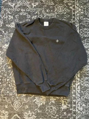 Svart sweatshirt från Polar skateboards - En svart sweatshirt från Polar skateboards med rund halsringning och liten broderad logga på bröstet. Tröjan har ribbade muddar vid ärmslut och nederkant. Perfekt för en avslappnad och stilren look.