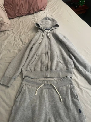  Polo Ralph Lauren dress - Säljer ett par gråa mjukisbyxor från Polo Ralph Lauren med dragsko i midjan och den klassiska blå loggan broderad på benet. Sköna och stilrena byxor i mjuk bomullsblandning, perfekta för chill dagar eller när du vill vara bekväm. Storlek M men passar även S