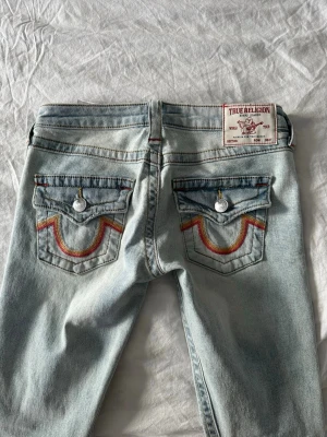 True Religion ljusblå bootcut jeans - Säljer ett par ljusblå jeans från True Religion med bootcut passform. Jeansen köptes i januari 2026 för runt 1500kr. 🤗 Säljer pga ska köpa nya mörkblåa. Kom med frågor och bud. Storlek 23.