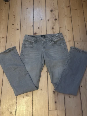 Gråa bootcut jeans från LTB - Säljer ett par gråa bootcut jeans från LTB med klassisk femficksdesign och normal midja. Jeansen har en snygg tvättad look och är tillverkade i bomull med lite stretch för extra komfort. Perfekta för dig som gillar avslappnad stil.