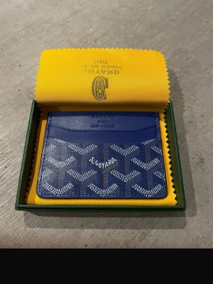 Blå kortfodral - Snyggt blått kortfodral med det klassiska vita och gråa mönstret. Tillverkat i exklusivt läder och har flera fack för kort. Kommer i original ask och med gul putsduk. Perfekt för dig som vill ha något stilrent och lyxigt i fickan.