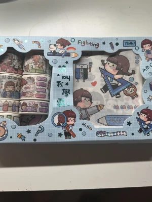 Sött washi tape och klistermärkesset - Set med flera rullar washi tape och matchande klistermärken i blå förpackning. Motiven är tecknade figurer, skolrelaterade prylar och söta detaljer i färger som blått, rosa och vitt. Perfekt för att dekorera anteckningsböcker, brev eller pyssel.