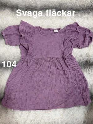 Ljuslila volangblus  - Ljuslila blus med volangdetaljer på axlarna och korta ärmar. Perfekt till jeans eller kjol.🌸 Svaga fläckar. Storlek 104