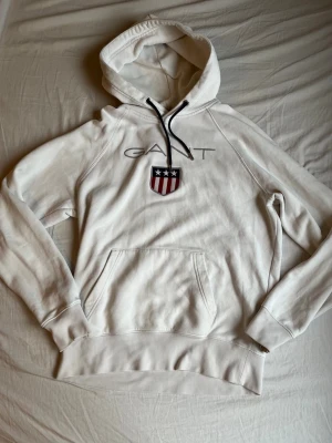 Vit hoodie från Gant - Säljer nu denna vita hoodie från Gant! En riktigt skön hoodie som funkar vid flera tillfällen. Den är i storlek M men passar S också. Hör av dig vid funderingar!