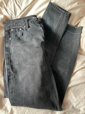 Svarta raka jeans från Object - Snygga svarta jeans från Object med rak passform och råa kanter nertill. Klassisk femficksmodell med silverfärgade nitar och dragkedja. Jeansen är i kraftigt denimtyg och har en cool, lite tvättad look.