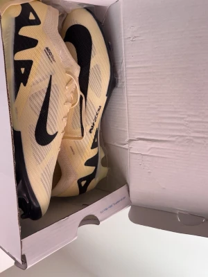 Nike Air Zoom Alphafly Elite - Säljer ett par Nike Air Zoom Alphafly Next% löparskor i ljusgul färg med svarta detaljer och stor svart Swoosh-logga. Skorna har en modern, aerodynamisk design och är tillverkade i meshmaterial för bra ventilation. Perfekta för dig som vill maxa din löpning.