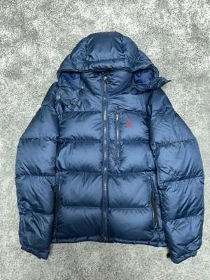 Polo Ralph Lauren Puffer Jacka - Stilren jacka i marinblått från Polo Ralph Lauren. Enkel att matcha och funkar året runt. OBS: Hand tighteners har torkats ut Skick: 8/10 Pris kan diskuteras 📦 Skickas eller möts upp.