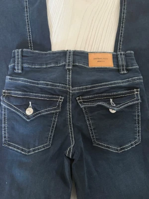 Blå jeans från Gina tricot - Snygga blå jeans från Perfect Jeans med kontrasterande vita sömmar och dekorativa ficklock bak. Klassisk femficksmodell med knapp och dragkedja framtill. Perfekta för dig som gillar en stilren men ändå detaljerad look.