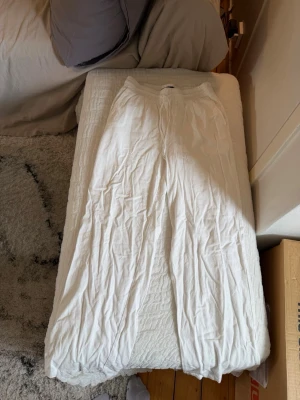 Vita vida linnebyxor - Snygga och luftiga vita linnebyxor med resår i midjan och raka, vida ben. Perfekta för en avslappnad och stilren look. Byxorna har en klassisk passform och är tillverkade i ett lätt och svalt linnematerial.