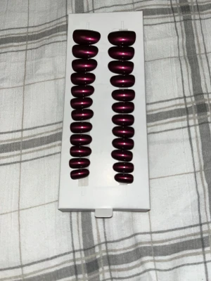 Mörklila press-on naglar Switch Nails - Snygga mörklila press-on naglar från Switch Nails. Naglarna har en glansig finish och en klassisk oval form. Tillverkade av återvunnet material och kan återanvändas. Perfekt för dig som vill ha en trendig look snabbt och enkelt. Oanvända bara öppnat och kollat 