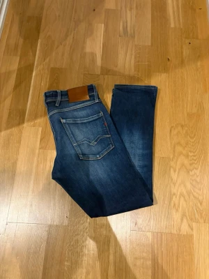 Mörkblå jeans från Replay - Snygga mörkblå jeans från replay med klassisk femficksdesign och kontrastsömmar. Jeansen har en rak passform och är tillverkade i denim med en liten läderpatch bak i midjan. Perfekta för en avslappnad och trendig look.