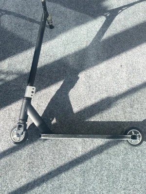 Svart kickbike i metall - Säljer en svart kickbike med två små hjul och robust ram i metall. Styret är rakt och har en enkel design utan extra detaljer. Perfekt för att cruisa runt i stan eller till skolan.