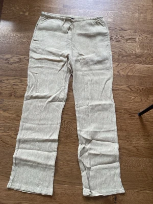 Beige linnebyxor med resårmidja H&M - Snygga beige linnebyxor med raka ben och resår i midjan. Byxorna har en avslappnad passform och är tillverkade i ett tunt, luftigt linnematerial som passar perfekt för varma dagar. Passar mig som är 177 cm lång.