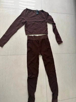 Brunt set med långärmad topp och tights - Ett brunt tränings sett från HM. Användning av den kanske 2 gånger och är i bra skick. Byxorna är högmidjade!