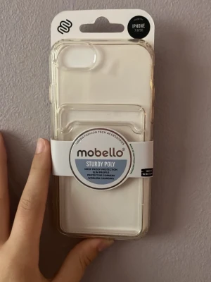 Mobello genomskinligt mobilskal i polykarbonat - Genomskinligt mobilskal från Mobello i tålig polykarbonat, designat för iPhone 7/8/SE. Skalets stilrena och slimmade form ger bra skydd mot stötar och repor, samtidigt som det är kompatibelt med trådlös laddning. Perfekt för dig som vill visa upp din mobil.