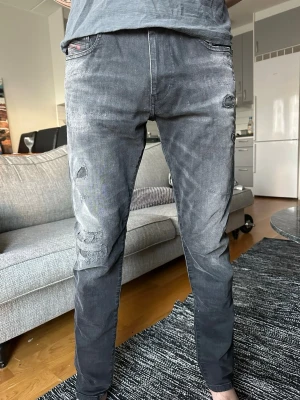 Diesel jeans - Mörkgråa jeans med slitna detaljer på låret och knät. Jeansen har en slimmad passform, märket Diesel. Storlek W31 L32💫