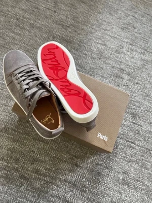 Gråa Christian Louboutin sneakers - Snygga gråa sneakers från Christian Louboutin i mocka med klassisk röd sula och vita kanter. Skorna har lågt skaft, matchande gråa skosnören och diskreta detaljer. Perfekta för dig som vill sticka ut med exklusiv stil och ikonisk design.