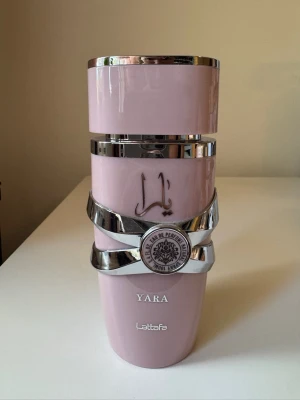 Yara parfym från Lattafa, rosa flaska - Säljer en Yara parfym från Lattafa i en snygg rosa flaska med silverdetaljer och dekorativa band. Flaskan har en modern design med både arabiska och engelska inskriptioner. Perfekt för dig som gillar unika och trendiga parfymer. Ca 95% kvar. 