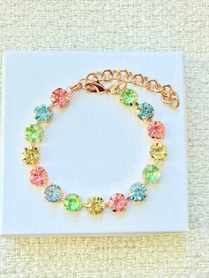 Armband med färgglada stenar  - Snyggt armband med runda stenar 8m stora i pastellfärger som rosa, blått, grönt och gult. Länken är guldfärgad och har ett justerbart spänne. Perfekt för dig som gillar färg och vill ha något unikt på handleden. Oanvänt! 