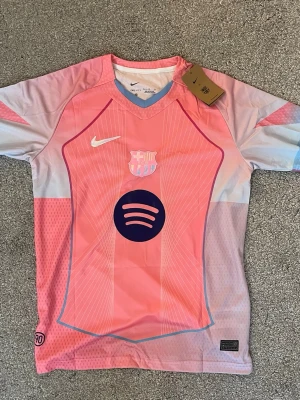 Barca rosa specialtröja Nike dri-FIT  - Säljer en rosa och ljusblå FC Barcelona matchtröja från Nike med Dri-FIT-material. Tröjan har klubbmärke, Nike-logga och Spotify-logga på bröstet samt V-ringning och korta ärmar. Perfekt för dig som älskar fotboll och vill sticka ut på planen. Bara skicka meddelande vid frågor👍
