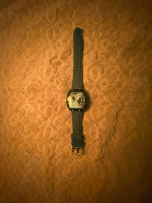 Mörkblå fyrkantig klocka med silikonband - Stilren klocka med svart fyrkantigt ur och matchande svart silikonarmband. Urtavlan har tydliga markeringar och detaljer i silver. Spännet är i metall och ger en snygg kontrast till det matta bandet. Perfekt accessoar för dig som gillar modern design.