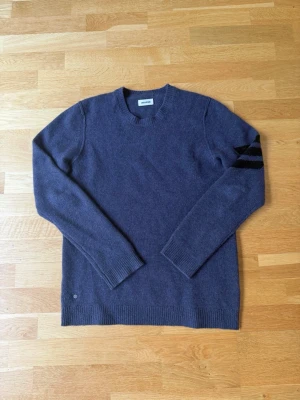 Mörkblå stickad tröja från Zadig Voltaire 100% Cashmere  - Mörkblå stickad tröja från Zadig Voltaire med rund halsringning och ribbade muddar. Tröjan har svarta ränder på ena ärmen som cool detalj. Nypris 4000+