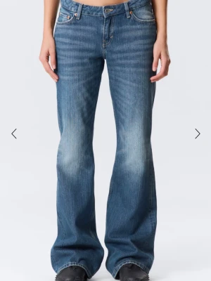 Blå bootcut jeans med slitningar - Snygga blå bootcut jeans med lätt slitna detaljer framtill. Jeansen har klassisk femficksdesign, låg midja. Tillverkade i denim med en autentisk tvätt för en avslappnad look. Model: Nova. W:26 L:34