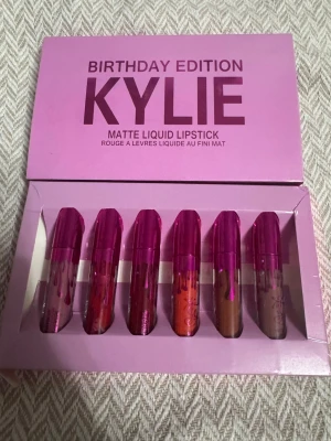 Kylie Birthday Edition läppstiftset - Säljer ett Kylie Birthday Edition Matte Liquid Lipstick set med sex flytande läppstift i olika nyanser. Förpackningen är lila och varje läppstift har en metallic rosa kork. Färgerna varierar från nude, röd, brun till orange och rosa. Perfekt för dig som vill ha flera val till läpparna.