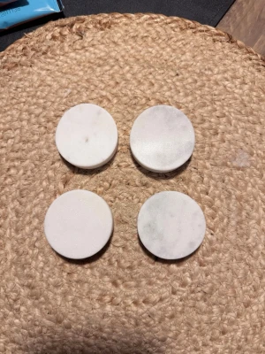 Runda vita marmorunderlägg för ätpinnar - Fyra stycken runda underlägg i vit marmor. De är tjocka och har en slät yta med naturliga marmormönster. Det är hållare för ätpinnar. 1 är använd 1 gång 