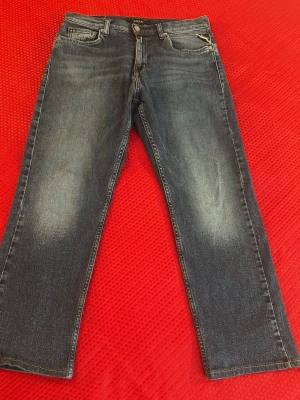 Blå raka jeans från Replay storlek 158 cm  - Snygga blå jeans från Replay med raka ben och klassisk femficksdesign. Jeansen har en lätt tvättad look med diskreta slitningar och detaljerad bakficka. Perfekta för en avslappnad och trendig stil.