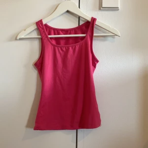 Rosa linnetopp med breda axelband - Enkel och snygg rosa linnetopp med breda axelband och rundad halsringning. Linnet har en figurnära passform. Står ingen storlek fast skulle gissa XXS