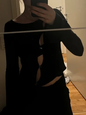 Svart topp  - Trendig svart topp med lång ärm och öppen framtill. Materialet är väldigt mjukt och bekvämt, storlek 36 men är mer som 34. I nyskick! 