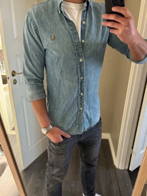 Ljusblå jeansskjorta från Polo Ralph Lauren - Säljer en ljusblå jeansskjorta från Polo Ralph Lauren, perfekt nu till våren 🌸Storlek L slim-fit. Tveka inte att kontakta vid funderingar, pris kan diskuteras? 💯
