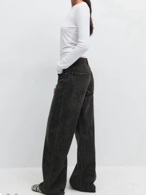 Svarta vida jeans med hög midja - Säljer ett par svarta jeans med breda ben och hög midja. Jeansen har klassisk femficksdesign och är tillverkade i denim med lätt tvättad look. Perfekta för en avslappnad och trendig stil.