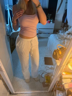 Vita lågmidjade linnebyxor  - Säljer ett par vita linnebyxor med avslappnad passform och dragsko i midjan. Byxorna har raka ben och elastisk midja för extra komfort. Perfekta för en chill och stilren look. Materialet är lätt och luftigt linne.