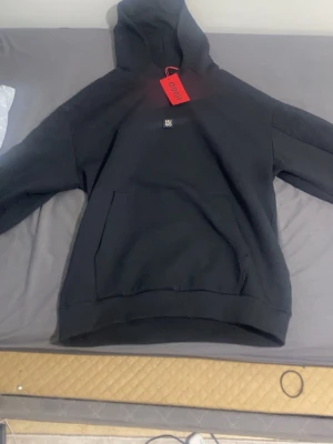 Svart hoodie från Hugo med logga. - Svart hoodie från Hugo med liten logga på bröstet och diskret mönster längs ärmarna. Klassisk huva och stor magficka framtill. Perfekt för dig som gillar stilrena och moderna plagg. Tröjan är ingen replika.