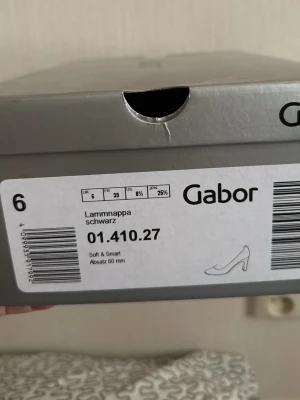 Svarta pumps i lammnappa från Gabor - Klassiska svarta pumps från Gabor i mjukt lammnappaläder. Skorna har en elegant spetsig tå och en smal klack på 60 mm som ger en stilren siluett. Perfekta för dig som vill ha en tidlös och bekväm sko i högkvalitativt material.