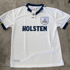  Tottenham Hotspur 1994/95 hemmatröja - Säljer en vit Tottenham Hotspur matchtröja med mörkblå detaljer och gul rand på ärmarna. Tröjan har klubbmärke på bröstet, HOLSTEN-tryck på magen och mörkblå krage. Helt ny med prislapp och köpt från tottenhams hemsida⚪️Hör av er vid frågor✅