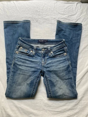 Miss Me bootcut jeans  - Supersnygga Miss Me bootcut jeans i storlek 23! Köpta i USA och säljer eftersom de är för korta. Sammanlagt 3 stenar på fickorna där bak har ramlat av. (Se bilder)  Midjemått rakt över: ca 34-35cm  Innerbenslängd: 77cm  Bredd i lår: ca 21cm  Bredd längst ner på jeansen: 21cm  Skulle säga att de är mid rise. Är för korta för mig som är 163cm lång!  Inga hål eller fläckar vad jag vet.  Skriv för fler frågor 💕