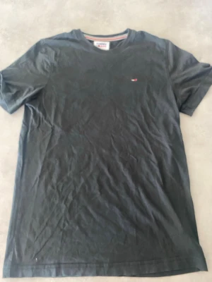 Mörkblå t-shirt från Tommy Hilfiger - Klassisk mörkblå t-shirt från Tommy Hilfiger med liten broderad logga på bröstet. T-shirten har rund halsringning och korta ärmar. Tillverkad i mjuk bomull som känns skön mot huden. Perfekt till jeans eller shorts.