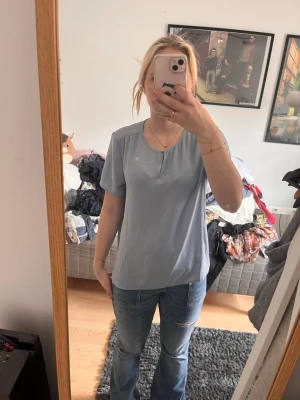 Ljusblå enkel kortärmad topp - En ljusblå topp med korta ärmar och rund halsringning. Toppen har en avslappnad passform och är tillverkad i ett mjukt bomullsliknande material. Perfekt att matcha med jeans för en clean och enkel look.