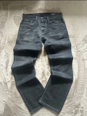 Jack & Jones vintage jeans - Säljer ett par riktigt snygga Jack & Jones vintage jeans i väldigt bra skick i färgen gråsvart, jag skulle säga att dom är mer åt slim fit hålet!  Mått: Längd:100cm Midjemått:39cm Benöppningen:19cm  Priset går alltid att diskutera och kolla gärna in mina andra plagg som jag har lagt ut!🤩