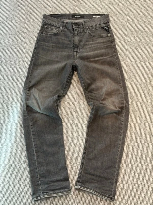 Grå jeans från Replay - Snygga grå jeans från Replay med klassisk femficksdesign och raka ben. Jeansen har en diskret tvättad look och är tillverkade i bomullsdenim. Perfekta för en avslappnad och trendig stil.